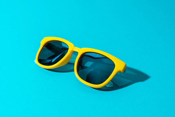 Sunglasses on turquoise blue background in perspective with hard shadow - 写真・画像