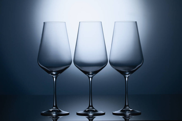 Empty wine glasses on a blue clean gradient background. Empty drinking transparent wine glasses - Photo, Image
