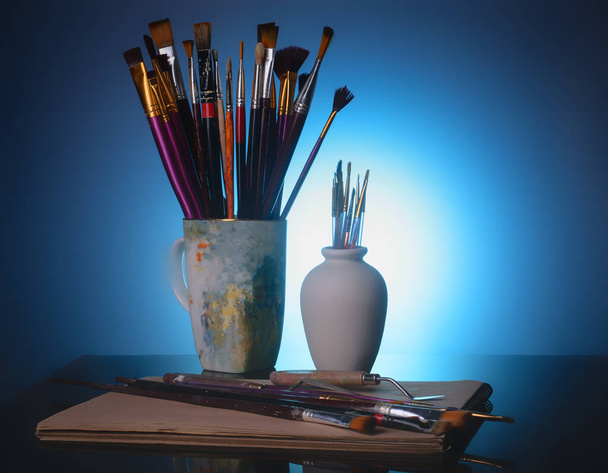 作家の道具-青の背景に筆とパレットナイフ - 写真・画像