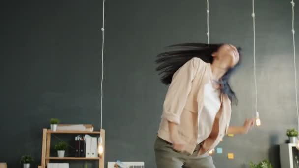 Playful businesswoman dancing on work table wearing trendy clothing having fun in workplace - Felvétel, videó