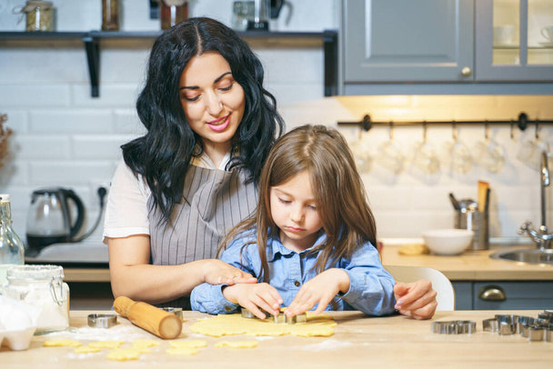 Happy family mother and daughter preparing homemade cookies in the kitchen. - Foto, Imagen