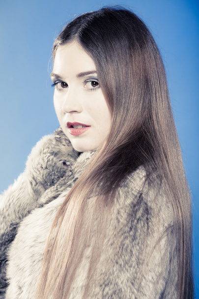 Portrait of girl with long hair. Young woman in fur coat on blue. - Fotoğraf, Görsel