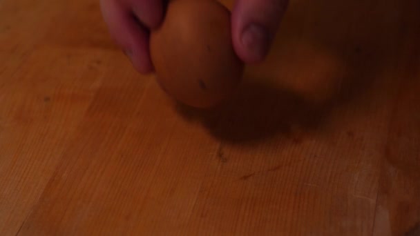 Мужская рука нажимает красное яйцо на деревянном фоне - Кадры, видео