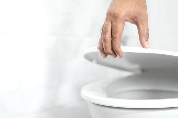 Man opens toilet seat with hand in the bathroom - Photo, image