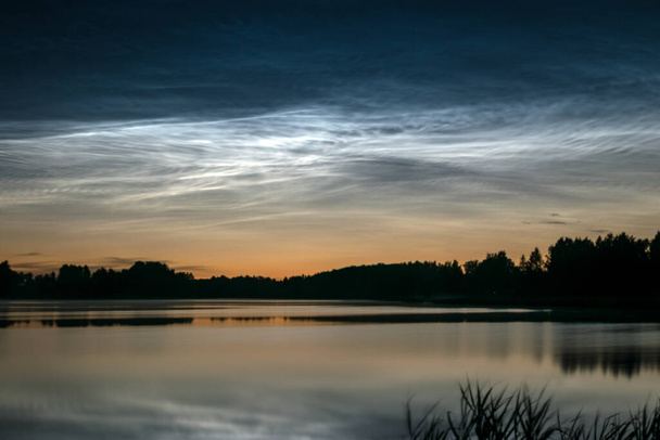 hermoso paisaje nocturno con nubes de plata blanca sobre el lago, primer plano borroso, encantadores reflejos de nubes en el agua del lago, noche de verano - Foto, imagen