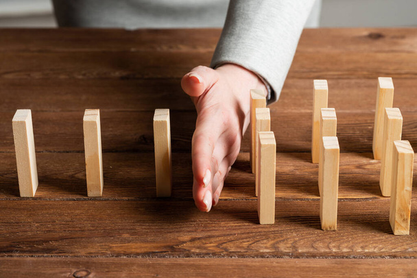 Businesswoman protecting dominoes from falling - Foto, Bild