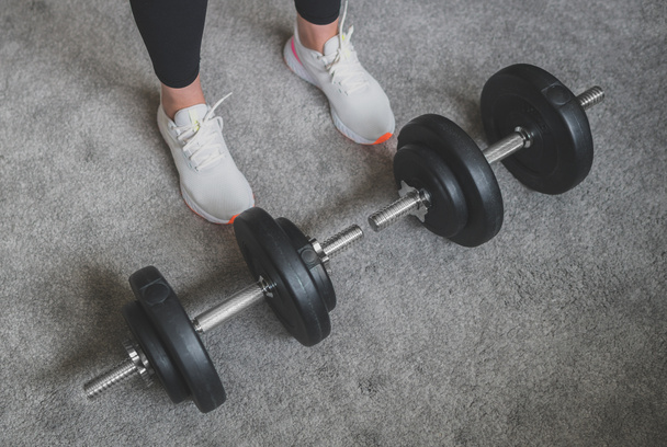 Woman is preparing to work out with dumbbells. Home fitness training concept. - Foto, Imagen