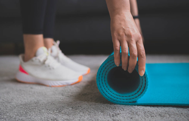 Woman rolling yoga mat. Home fitness training concept. - Foto, immagini