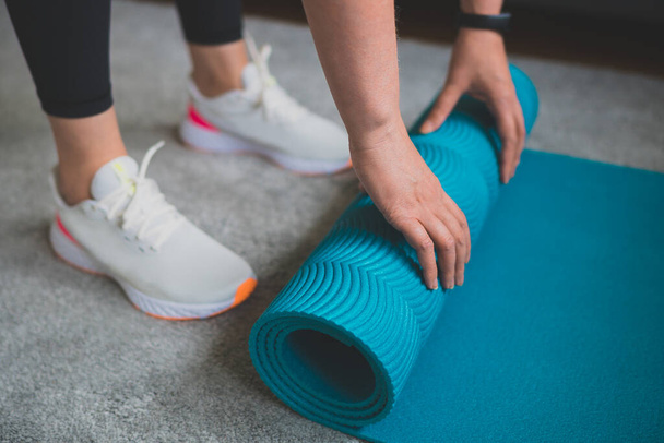 Woman rolling yoga mat. Home fitness training concept. - Foto, Imagem