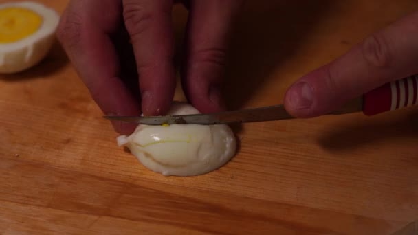 Mens handen snijden het geschilde ei in kleine stukjes  - Video