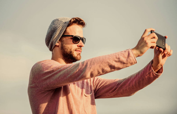 making photo. guy casual style. Fashion model. macho man use mobile phone. modern technology in life. always in touch. confident man speak on phone. Call to friend. sexy man selfie sky background - Valokuva, kuva