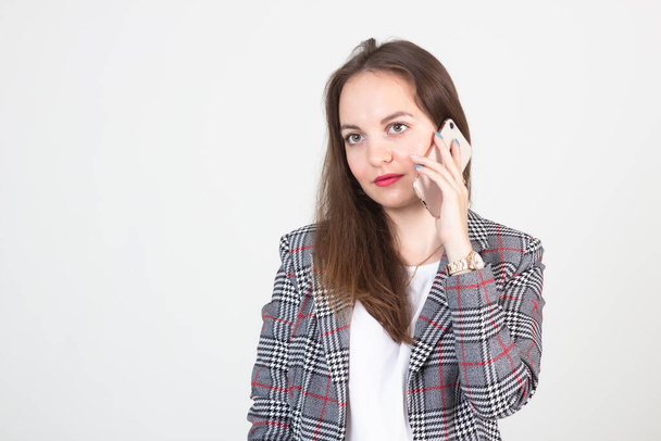 Bella giovane donna che lavora parlando al telefono su uno sfondo bianco - Foto, immagini