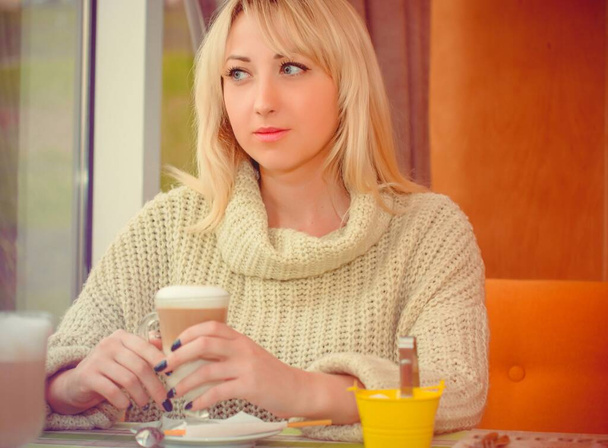 Woman sitting in a cozy cafe white coffee break, Woman enjoying coffee after hours, woman having breakfast in a cozy cafe in the early morning, Autumn mood, Christmas mood - Foto, imagen