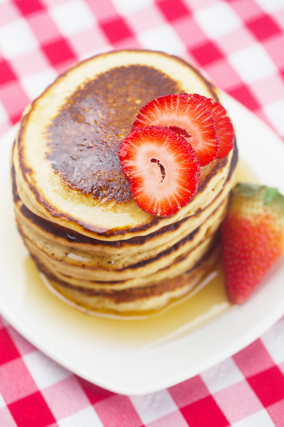 Pancakes, honey and strawberry on checkered fabric - Foto, afbeelding