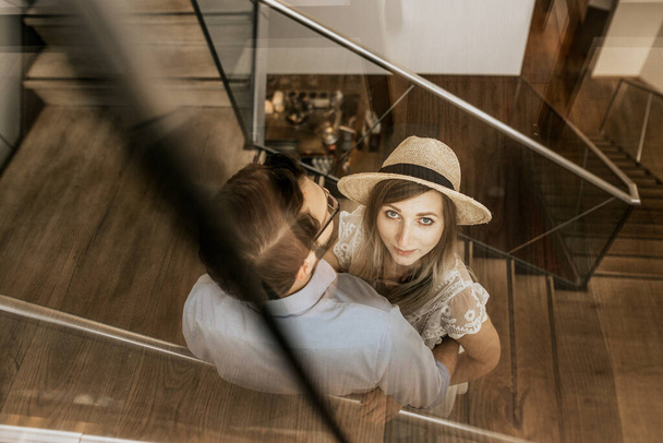 Close up stylish couple on stairs in restorant. Happy family up stairs and woman in white hat look in camera - Fotografie, Obrázek