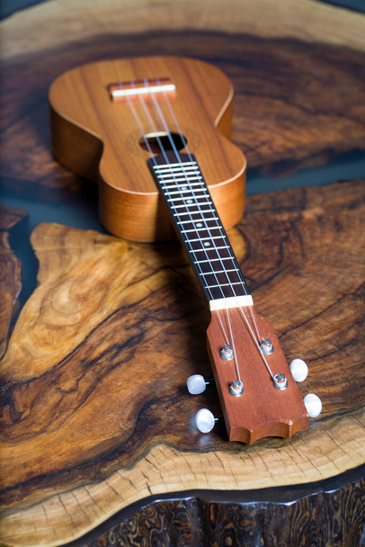 Soprano ukulele - klein lichtbruin instrument op mooie houten tafel - Foto, afbeelding