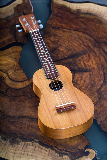 Kis hangszer - világosbarna ukulele gyönyörű fa asztalon. - Fotó, kép