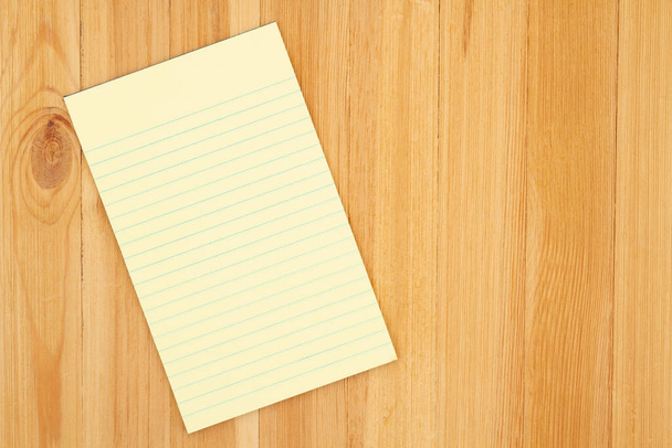 Gelbes Notizblock-Papier mit Linien auf Kiefernholz Schreibtisch mit Kopierraum für Ihr Unternehmen oder Schreiben von Nachrichten oder Attrappen - Foto, Bild