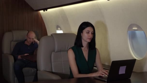 Successful businesswoman lawyer is working with laptop and tablet sitting in airplane interior.  - Кадры, видео