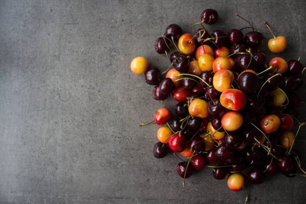 Beautiful juicy cherries border or frame. Dark grey textured background with copy space. Summer fruits close up. Healthy eating concept.  - Photo, Image