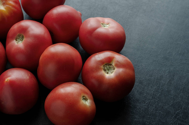 Reife rote Tomaten auf schwarzem Hintergrund. Demonstration der Ernte von landwirtschaftlichen Produkten. Gesunde Ernährung. Die Agrarindustrie. Kopierraum - Foto, Bild
