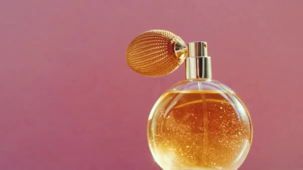 Luxury golden perfume bottle and shining light flares on pink background, glamorous fragrance scent as perfumery product for cosmetic and beauty brand - Footage, Video