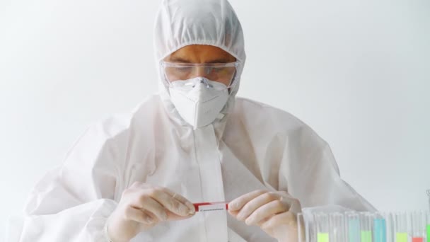 Doctor in protective suit showing coronavirus infected blood sample test tube - Materiał filmowy, wideo