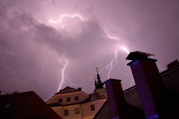 Blitze vor Gebäuden, violetter Himmel in der Stadt - Foto, Bild
