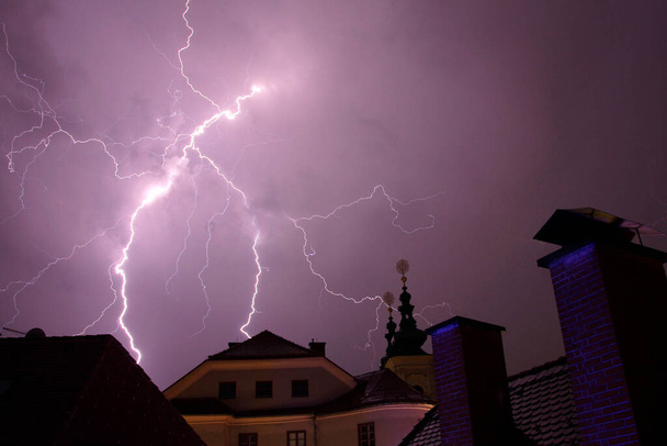 thunderbolts in front of buildings, purple sky in the city - Photo, Image