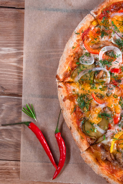 Appetizing pizza on a wooden table surrounded by herbs and spices. The concept of delicious food, restaurants and cafes - Foto, Bild