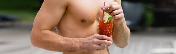 panoramisch gewas van shirtloze man die glas vasthoudt met cocktail  - Foto, afbeelding