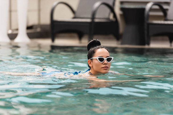 attractive young woman in sunglasses swimming in pool  - Foto, afbeelding