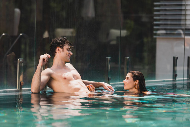 γυμνόστηθος άντρας κοιτάζει ελκυστική γυναίκα στην πισίνα - Φωτογραφία, εικόνα