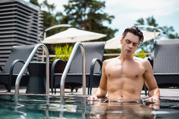 水泳プールを見下ろすセクシーで筋肉質の男の選択的な焦点 - 写真・画像