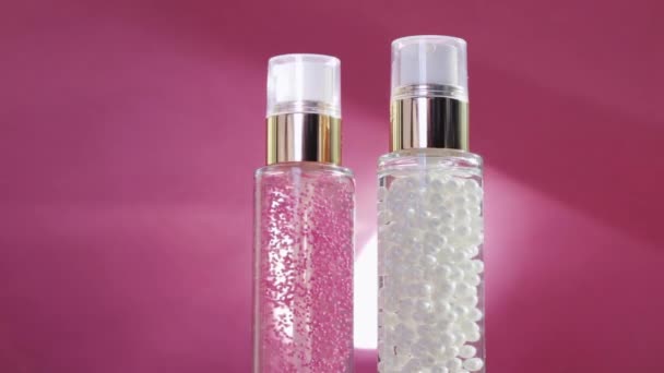 Productos de cuidado de la piel de lujo y bengalas de luz brillante sobre fondo rosa, base de maquillaje y gel de suero como rutina de cuidado de la piel para cosméticos faciales y marca de belleza
 - Metraje, vídeo