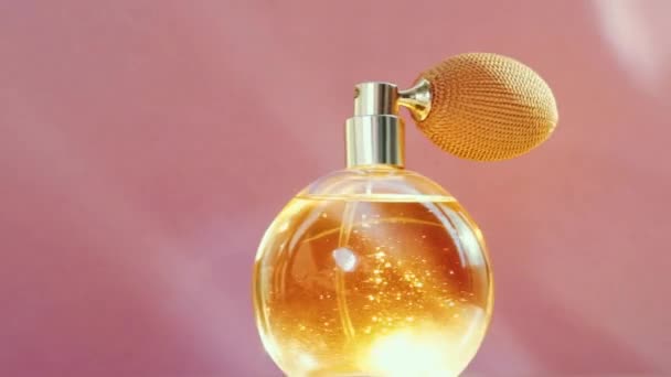 Luxuriöse goldene Parfümflasche und leuchtende Lichterketten auf rosa Hintergrund, glamouröser Duftduft als Parfümerieprodukt für Kosmetik- und Schönheitsmarken - Filmmaterial, Video