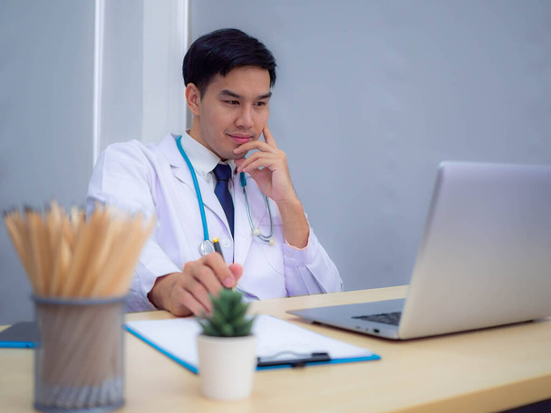 Doktor pracující v kanceláři, profesionální lékař sedící za stolem v bílé uniformě pracující v kanceláři. - Fotografie, Obrázek