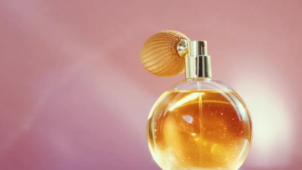 Luxus arany parfüm palack és csillogó fény fáklyák rózsaszín háttér, elbűvölő illat, mint parfüm termék kozmetikai és szépségápolási márka - Felvétel, videó