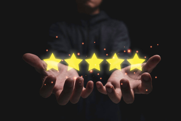 Бізнесмен тримає п'ять золотих зірок. Огляд оцінки клієнтів та концепція задоволення
. - Фото, зображення