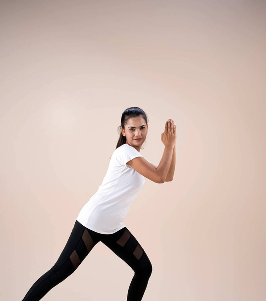 Молодая красивая леди в спортивной одежде, стоя ноги aparts коленях, поднять руки вверх рядом с ее лицом, немного повернутый, танцы тренировки для упражнений, с счастливым чувством
 - Фото, изображение