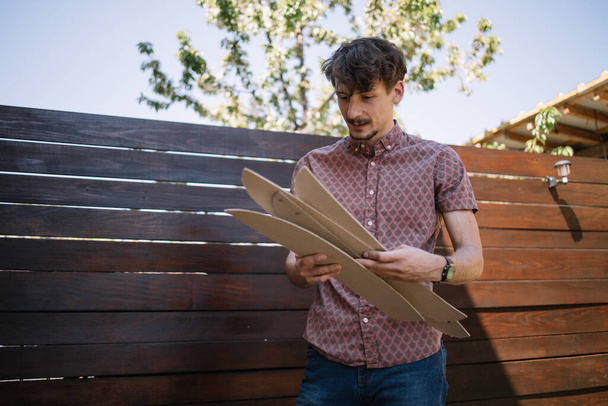 Young man holding wooden board in backyard - Foto, afbeelding