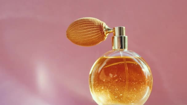 Luxury golden perfume bottle and shining light flares on pink background, glamorous fragrance scent as perfumery product for cosmetic and beauty brand - Footage, Video