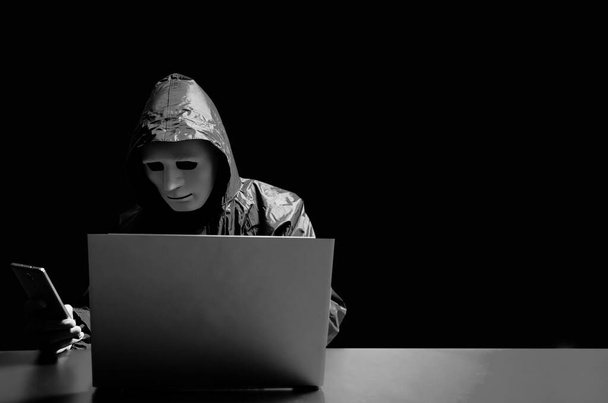 Anonieme computer hacker in wit masker en hoodie. Obscured dark face die mensen aanvalt via een smartphone. contact opnemen met victom door te sms 'en en te vragen om meer geld, Data dief, internet aanval, darknet en cyber security concept. - Foto, afbeelding