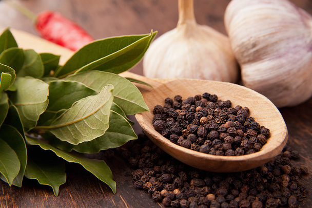 Pepper in wooden spoon with garlic, bay leaves - Foto, immagini