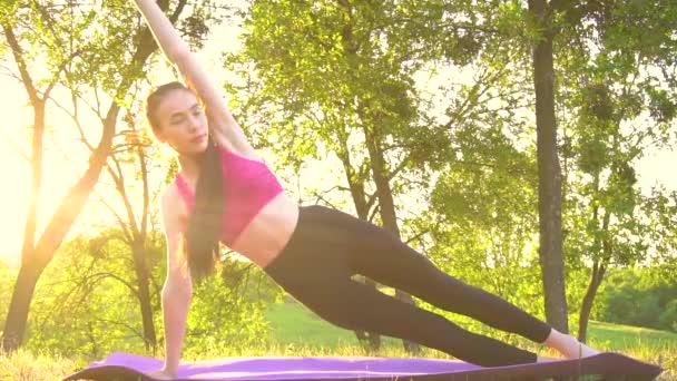 Žena ve sportovním oblečení cvičí jógu v parku západu slunce. - Záběry, video