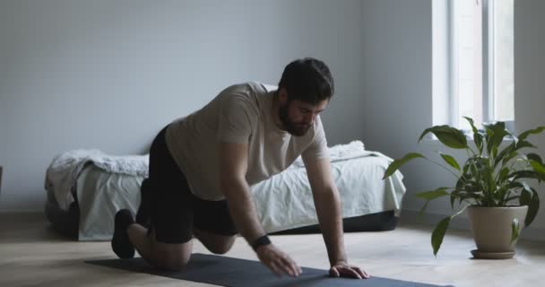 Giovane uomo che si estende sul tappeto fitness a casa - Filmati, video