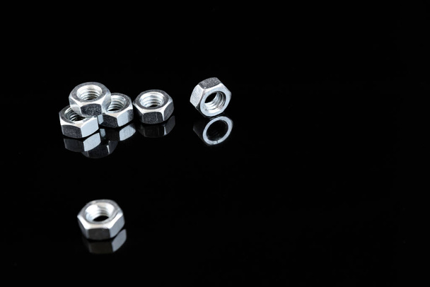Metal chrome bolts and nuts isolated on black background with copy space. - Foto, immagini