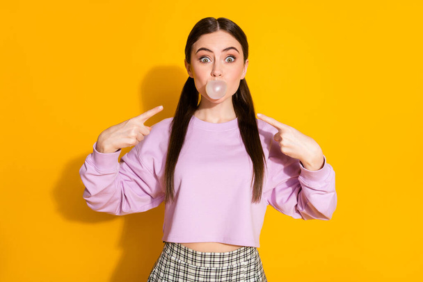 Portrait of shocked excited youth girl chewing bubble gum blowing impressed point index finger wear good look pullover isolated over vibrant color background - Foto, immagini
