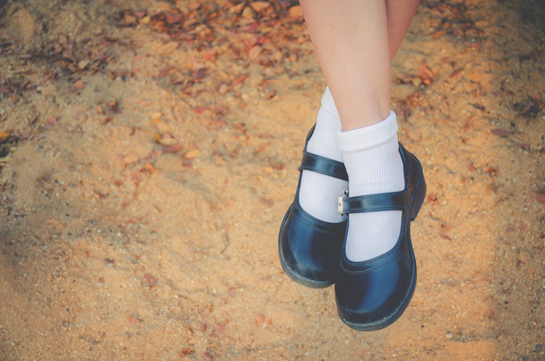 Kızın ayakları siyah bir öğrenci ayakkabısı giyiyor. - Fotoğraf, Görsel