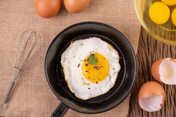 Жареные яйца в сковороде и сырые яйца, органические продукты для хорошего здоровья, высокий уровень белка - Фото, изображение